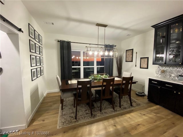 dining room featuring a barn door and light hardwood / wood-style flooring