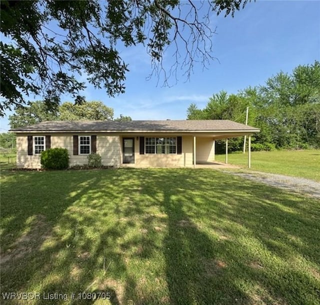 view of front of house featuring an attached carport, a front lawn, and gravel driveway