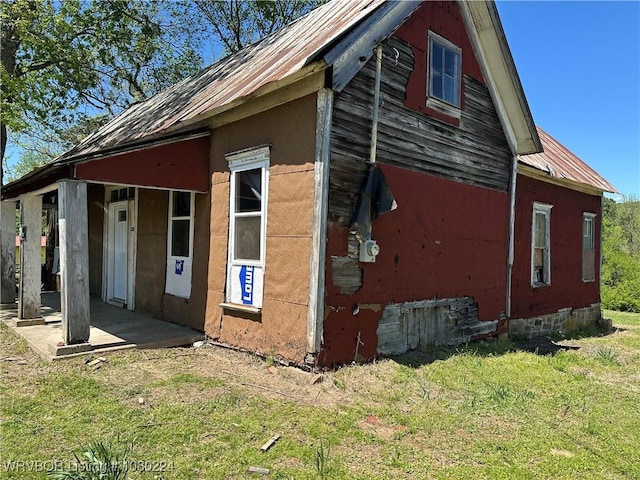 view of side of home with a yard, metal roof, and crawl space