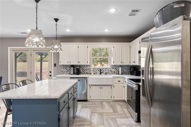 kitchen featuring appliances with stainless steel finishes, a breakfast bar, decorative light fixtures, a center island, and white cabinetry