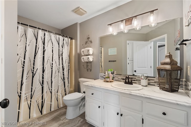 full bathroom with tasteful backsplash, vanity, shower / bath combo with shower curtain, hardwood / wood-style flooring, and toilet