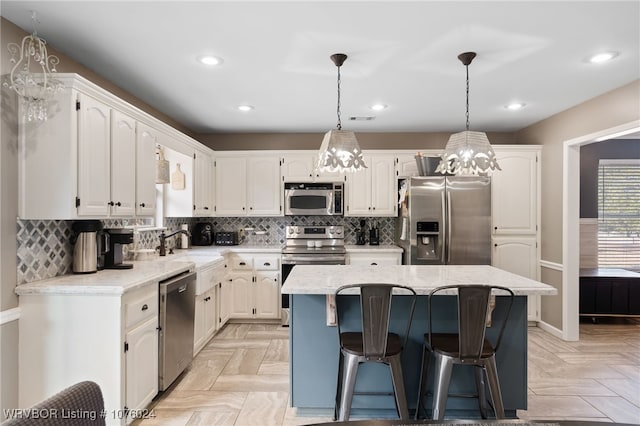 kitchen featuring sink, a center island, pendant lighting, white cabinets, and appliances with stainless steel finishes