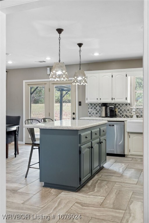 kitchen with tasteful backsplash, stainless steel dishwasher, pendant lighting, a center island, and white cabinetry