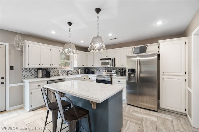 kitchen featuring hanging light fixtures, a kitchen island, a kitchen bar, white cabinetry, and stainless steel appliances