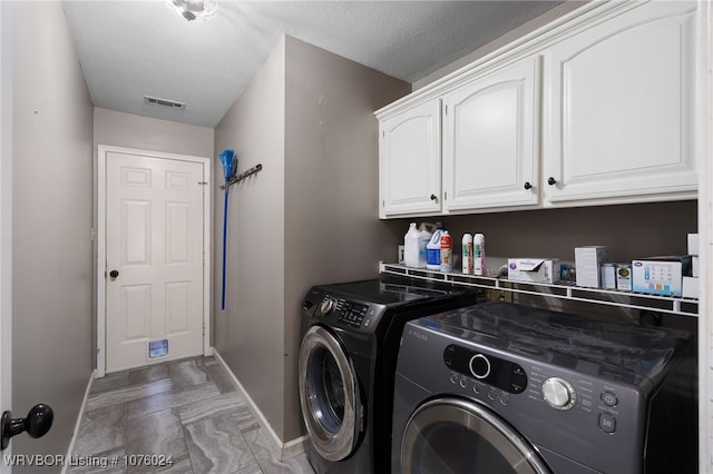 laundry area featuring cabinets, independent washer and dryer, and a textured ceiling