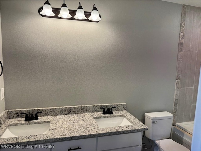 full bath with toilet, double vanity, and a sink