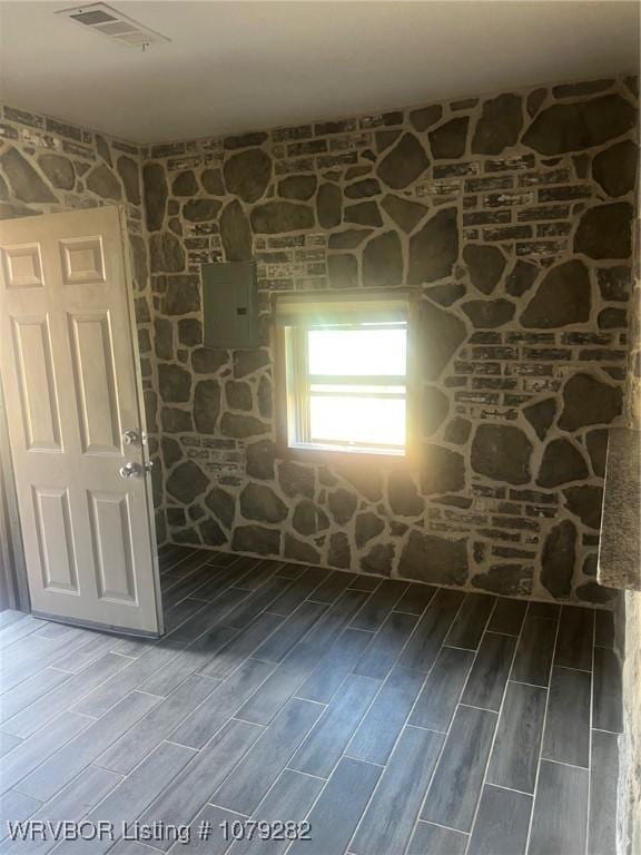 empty room featuring electric panel, visible vents, and wood tiled floor