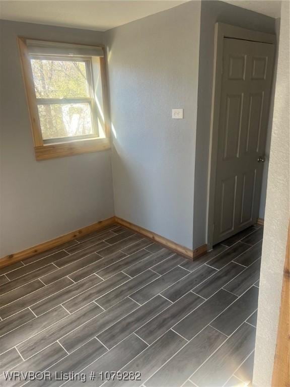 spare room featuring wood finish floors and baseboards