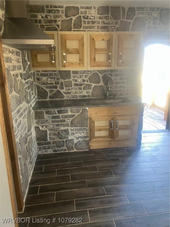 bar featuring wall chimney range hood, a sink, and wood tiled floor