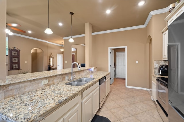 kitchen with arched walkways, tasteful backsplash, appliances with stainless steel finishes, and a sink