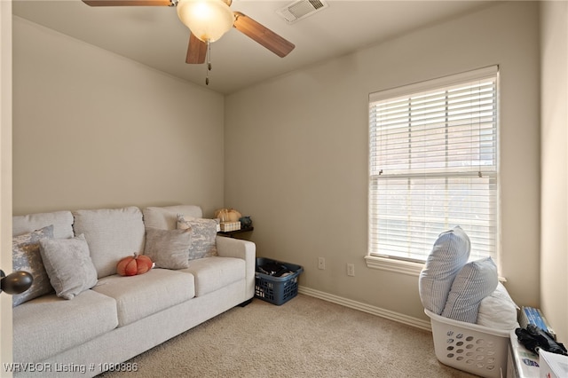 interior space featuring baseboards, a ceiling fan, visible vents, and light colored carpet