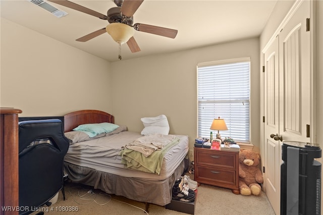 bedroom with light colored carpet, a ceiling fan, and visible vents