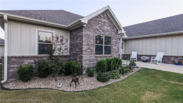 view of side of home featuring a lawn and a patio area