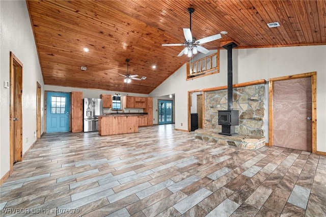 unfurnished living room with high vaulted ceiling, a wood stove, ceiling fan, and wooden ceiling