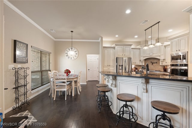 kitchen with a kitchen bar, appliances with stainless steel finishes, dark hardwood / wood-style flooring, decorative backsplash, and hanging light fixtures