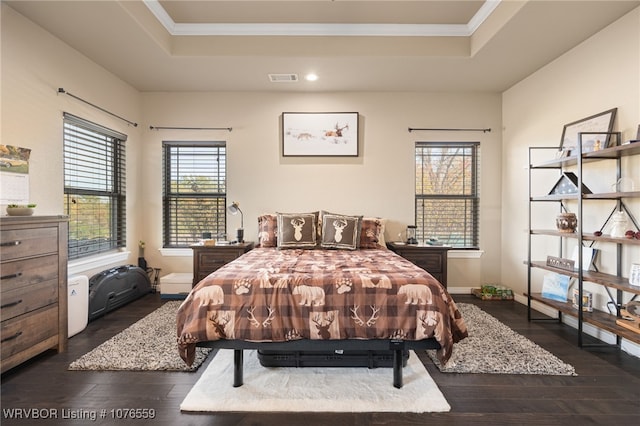 bedroom with dark hardwood / wood-style flooring, ornamental molding, and a tray ceiling