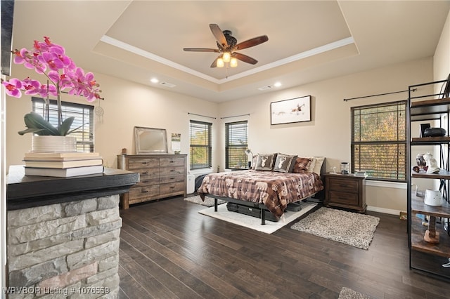 bedroom featuring ceiling fan, a raised ceiling, ornamental molding, and dark wood-type flooring