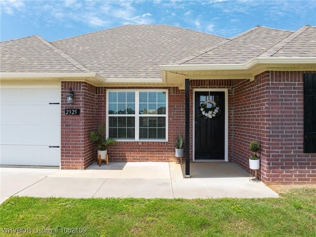 2325 Amy Ln, Van Buren, AR 72956 - view of exterior entry with brick siding, a garage, and roof with shingles