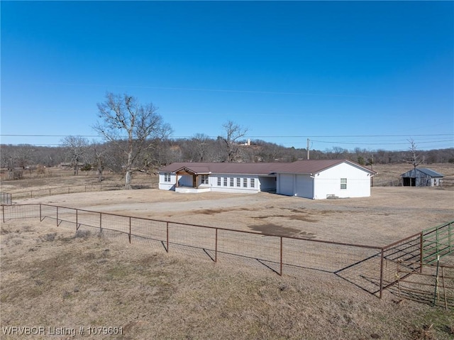 exterior space featuring a rural view, dirt driveway, and fence