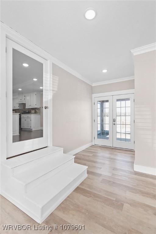 interior space with french doors, baseboards, ornamental molding, and light wood finished floors