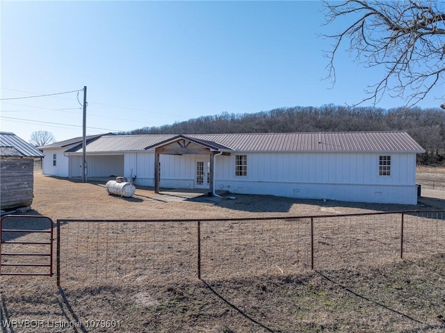 view of front facade with fence, french doors, metal roof, board and batten siding, and crawl space