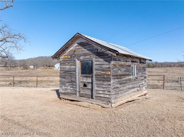 view of shed with a rural view and fence