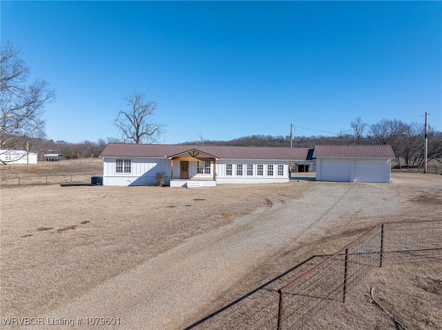 view of front of property featuring fence, dirt driveway, and metal roof