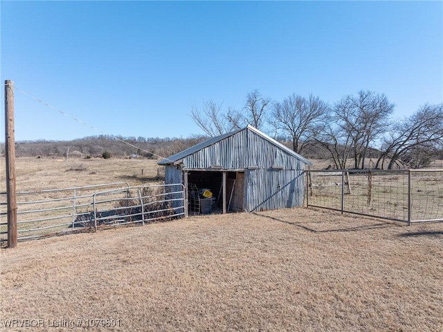 view of outbuilding with a rural view, an outdoor structure, and fence