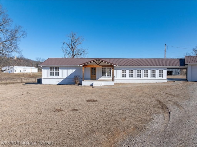 view of front of home with metal roof, an attached carport, cooling unit, and fence