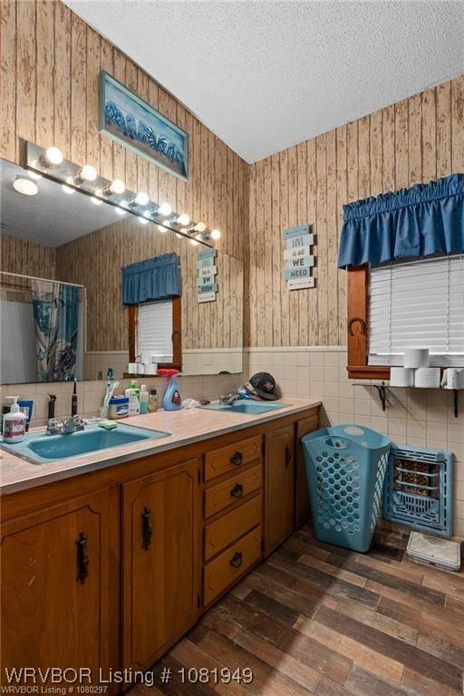1120 Second St, Charleston, AR 72933 - full bathroom featuring double vanity, a textured ceiling, wood finished floors, wainscoting, and a shower with shower curtain