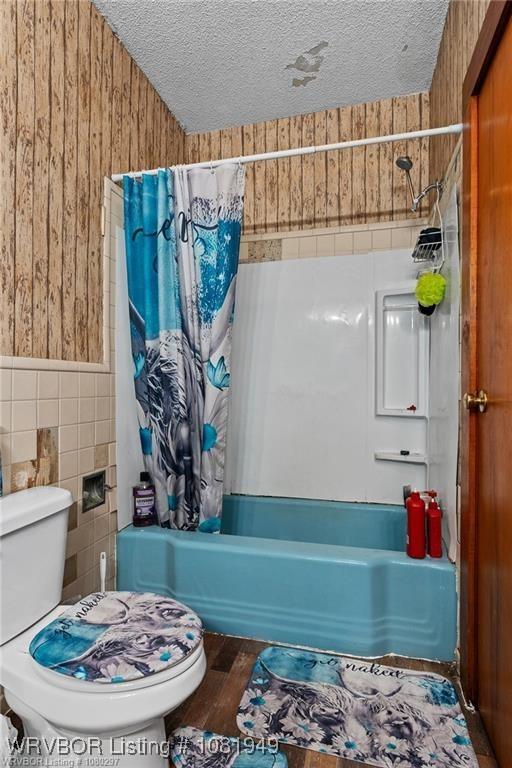 1120 Second St, Charleston, AR 72933 - full bathroom with shower / bath combo with shower curtain, tile walls, a textured ceiling, wood finished floors, and wooden walls