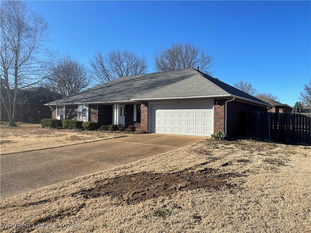 single story home with concrete driveway, brick siding, an attached garage, and fence