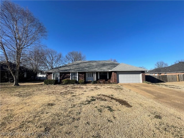 view of front of home featuring a garage, fence, concrete driveway, and brick siding