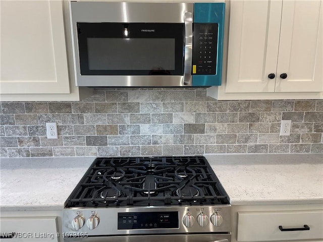 kitchen featuring decorative backsplash, stainless steel appliances, light stone counters, and white cabinets