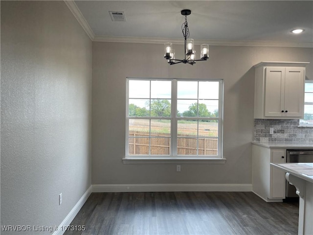 unfurnished dining area featuring dark hardwood / wood-style flooring, crown molding, plenty of natural light, and a notable chandelier