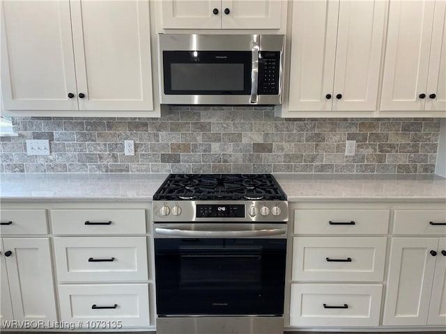 kitchen featuring stainless steel appliances, white cabinetry, and tasteful backsplash