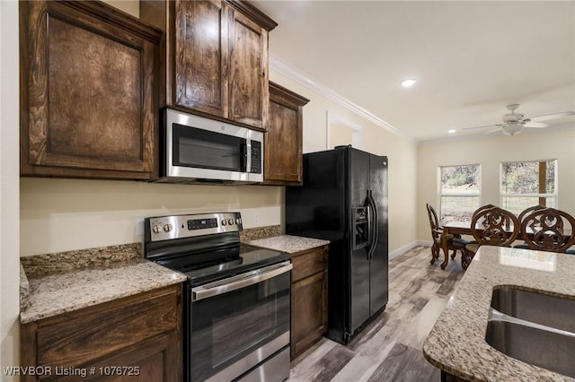 kitchen featuring light stone countertops, ceiling fan, stainless steel appliances, and light wood-type flooring