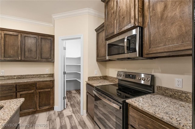 kitchen featuring light stone countertops, crown molding, stainless steel appliances, and light wood-type flooring