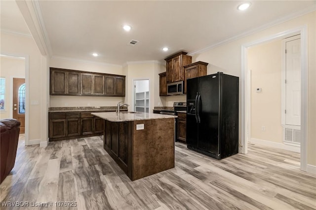 kitchen with a kitchen island with sink, sink, appliances with stainless steel finishes, light hardwood / wood-style floors, and dark brown cabinetry