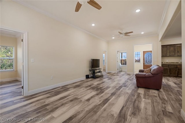 living room featuring crown molding, ceiling fan, and light wood-type flooring