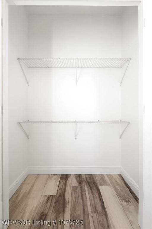 walk in closet with hardwood / wood-style flooring