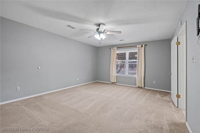 empty room featuring visible vents, ceiling fan, light carpet, and baseboards