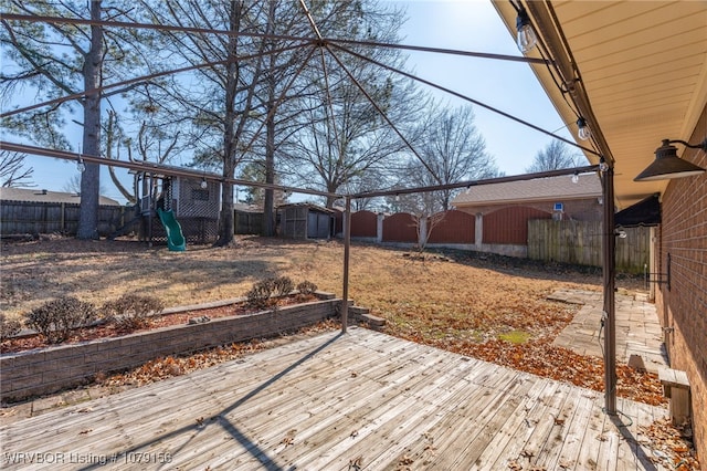 view of yard featuring a deck, a playground, and a fenced backyard