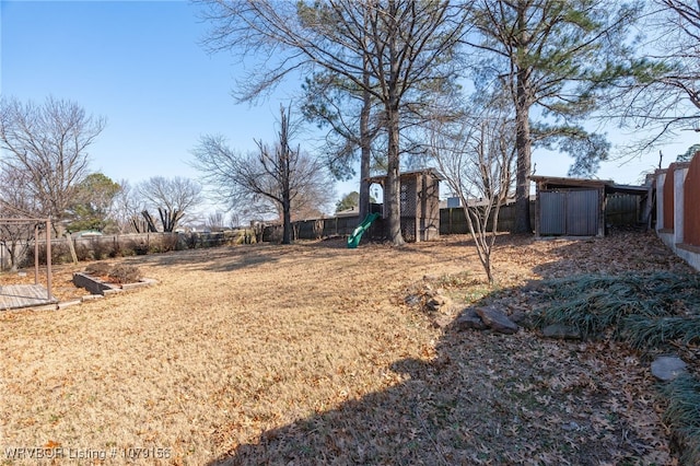 view of yard with a fenced backyard, a shed, and an outbuilding