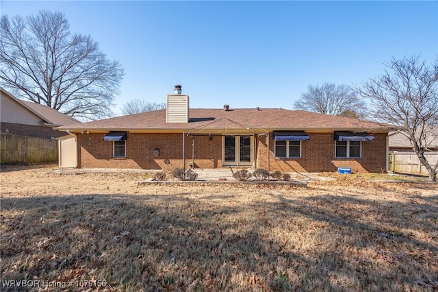 rear view of house with a chimney, fence, a patio, and brick siding