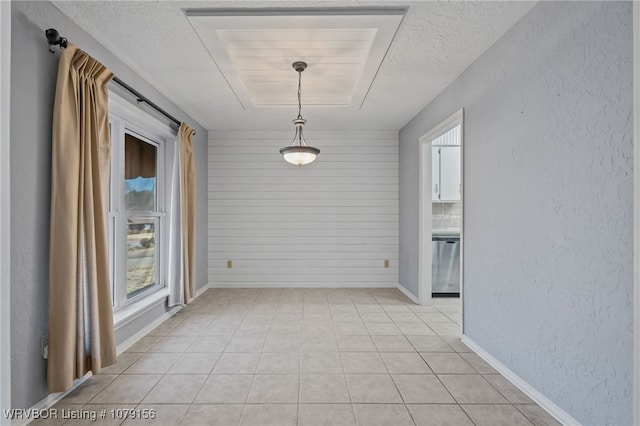 unfurnished dining area with baseboards, a tray ceiling, a textured ceiling, and a textured wall