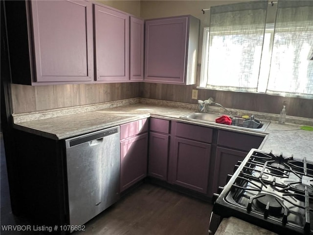 kitchen featuring stainless steel dishwasher, black gas stove, sink, and dark wood-type flooring