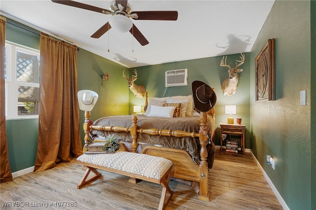 bedroom with ceiling fan, light wood-type flooring, and a wall mounted AC