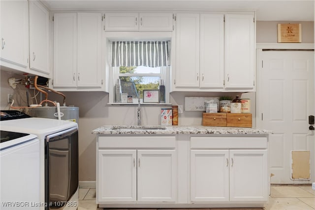 washroom with sink, cabinets, water heater, independent washer and dryer, and light tile patterned floors