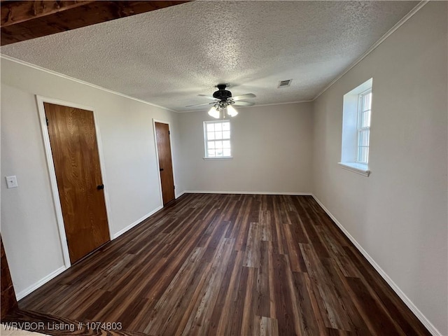 empty room with a textured ceiling, dark hardwood / wood-style flooring, ceiling fan, and ornamental molding